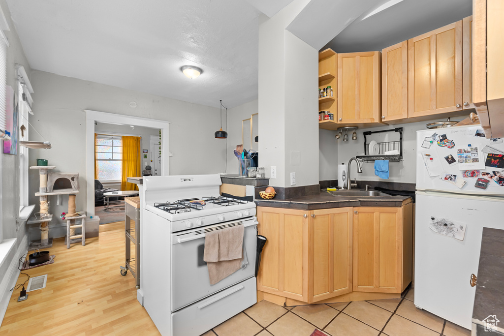 Kitchen featuring open shelves, a sink, a peninsula, light brown cabinets, and white appliances