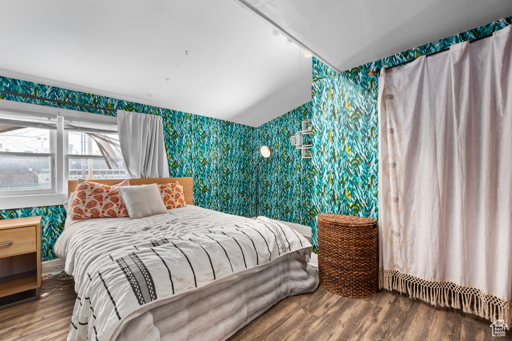 Bedroom with wallpapered walls and wood finished floors