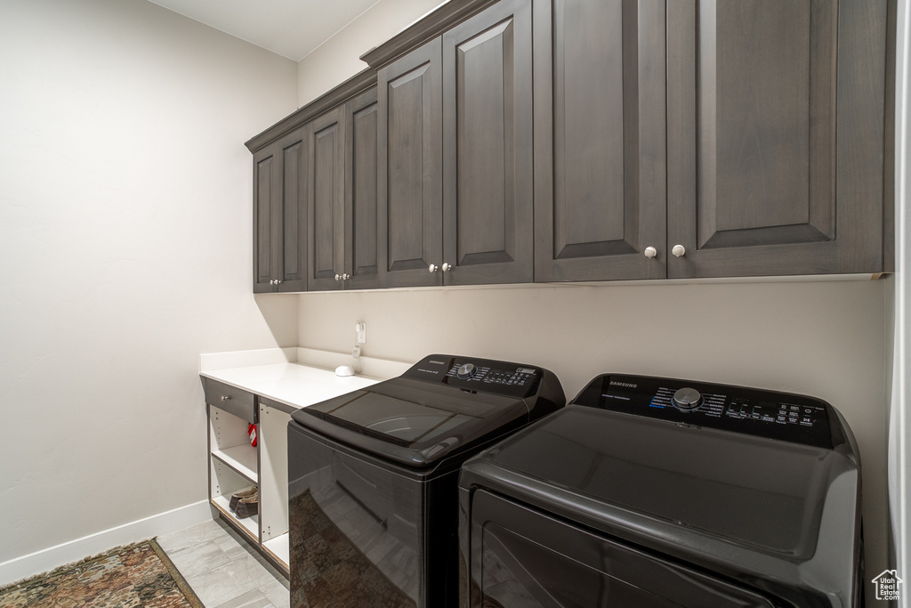 Laundry area with cabinet space, baseboards, and washer and clothes dryer