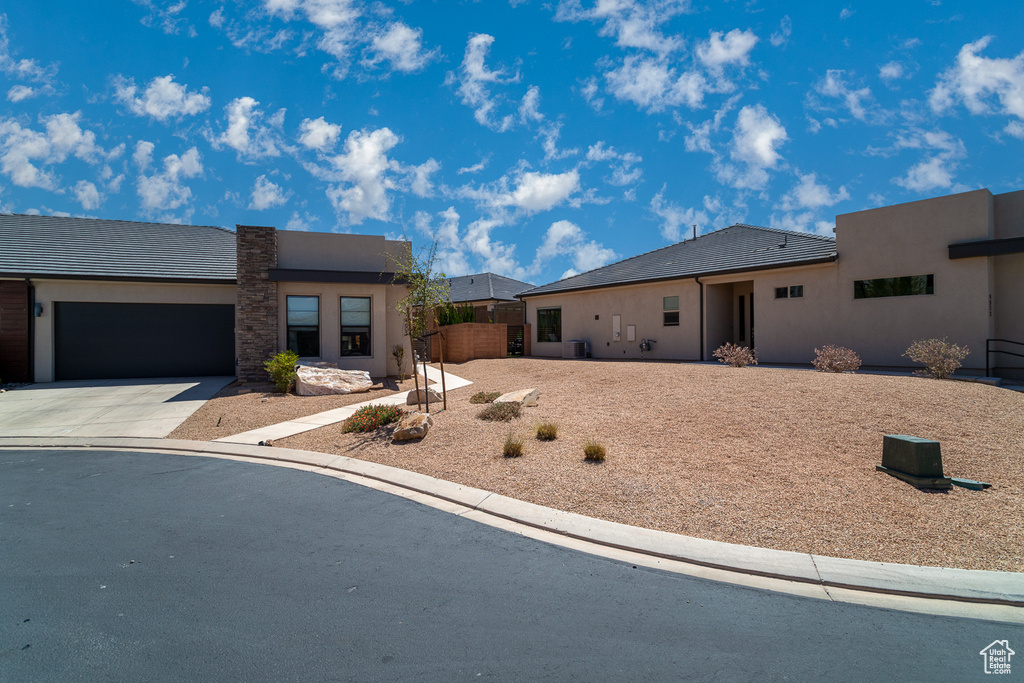 Ranch-style home with concrete driveway, an attached garage, and stucco siding