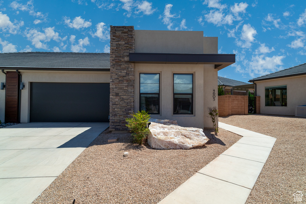 View of front of house with fence, an attached garage, stucco siding, and concrete driveway