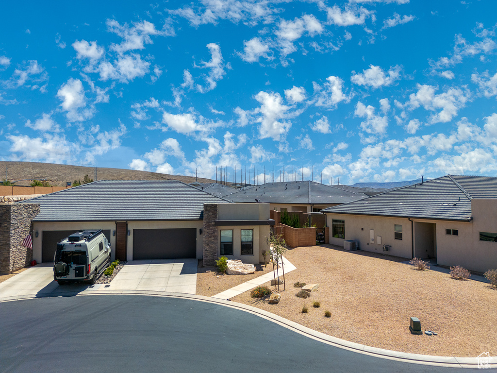 Ranch-style house with a tiled roof, an attached garage, driveway, and stucco siding