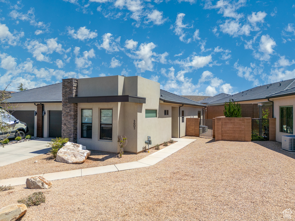 View of front facade with a gate, a garage, fence, concrete driveway, and stucco siding