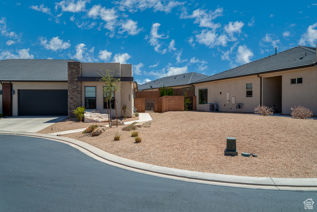 View of front of home featuring a garage, fence, stucco siding, and driveway