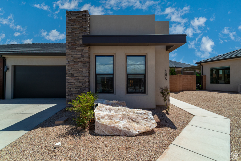 Contemporary home featuring fence, an attached garage, driveway, and stucco siding
