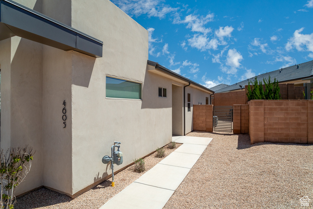 View of side of home featuring a gate, stucco siding, and fence
