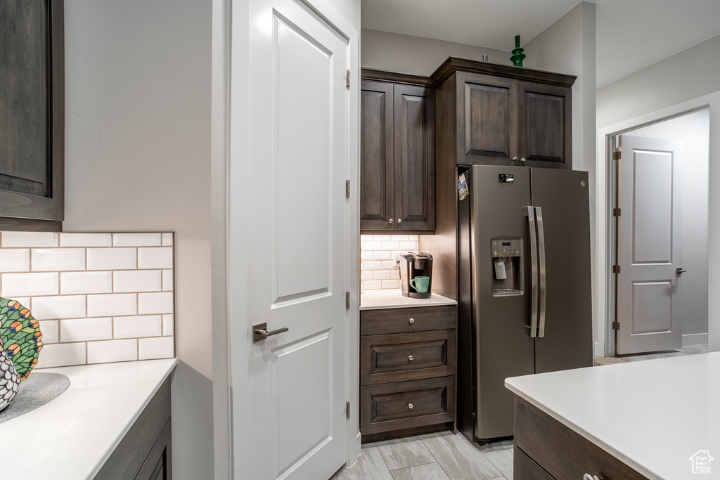 Kitchen featuring light countertops, stainless steel fridge with ice dispenser, tasteful backsplash, and dark brown cabinets