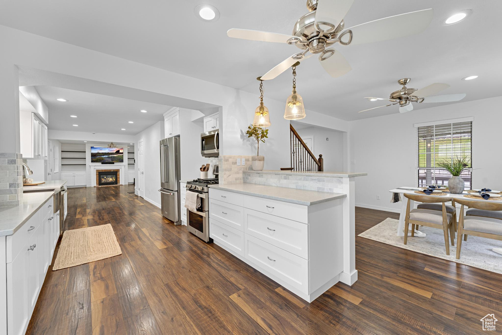 Kitchen with appliances with stainless steel finishes, ceiling fan, decorative backsplash, and a peninsula