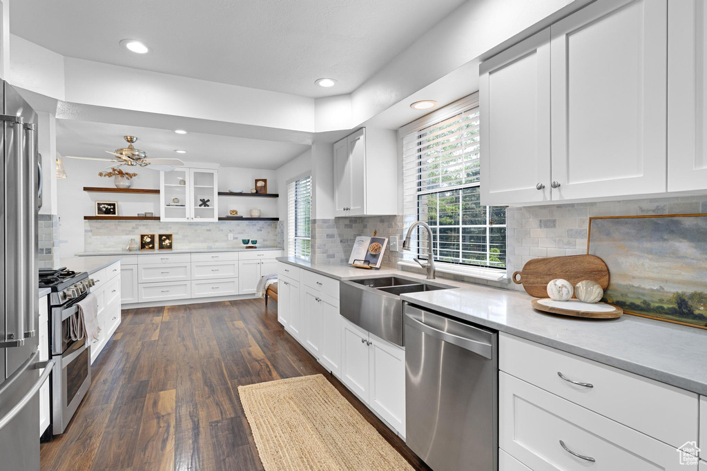 Kitchen featuring open shelves, white cabinetry, a sink, dark wood finished floors, and stainless steel appliances