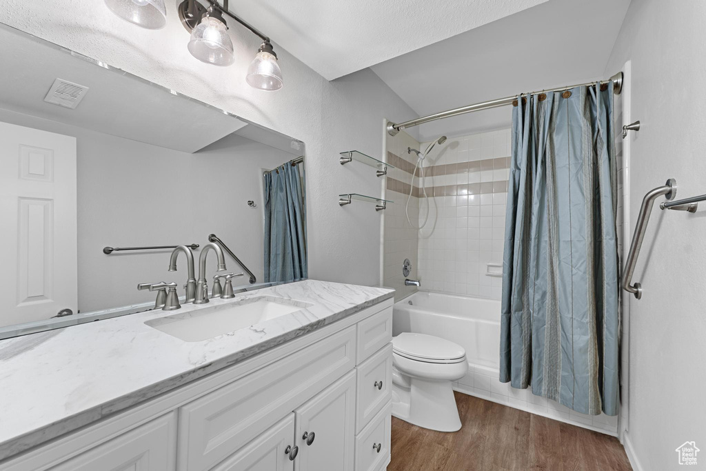 Full bathroom featuring visible vents, vanity, wood finished floors, toilet, and shower / bathtub combination with curtain