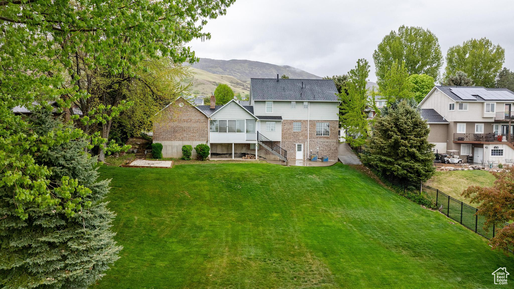 Back of property with a sunroom, stairway, fence, a mountain view, and a yard