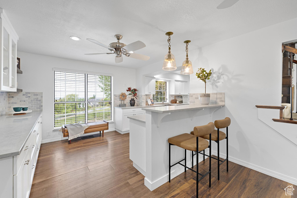 Kitchen with ceiling fan, backsplash, a peninsula, and a kitchen breakfast bar
