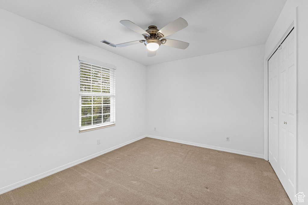 Unfurnished bedroom with a ceiling fan, visible vents, baseboards, a closet, and carpet