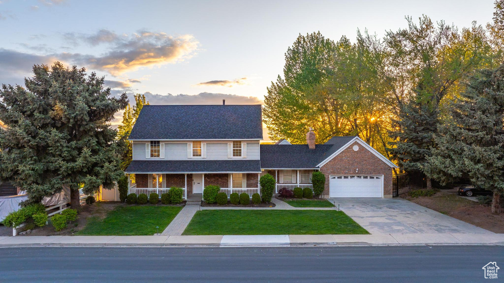 Traditional home with a shingled roof, an attached garage, a chimney, concrete driveway, and a lawn