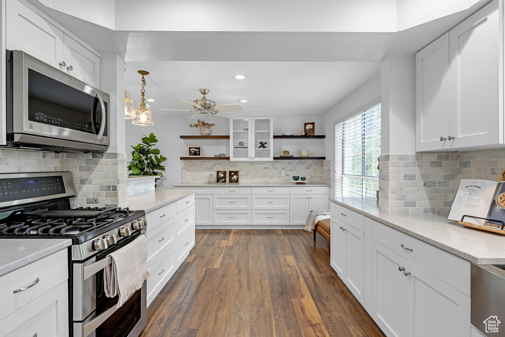Kitchen featuring open shelves, appliances with stainless steel finishes, ceiling fan, dark wood-type flooring, and backsplash