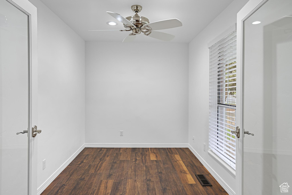 Empty room with ceiling fan, dark wood-style flooring, visible vents, baseboards, and recessed lighting