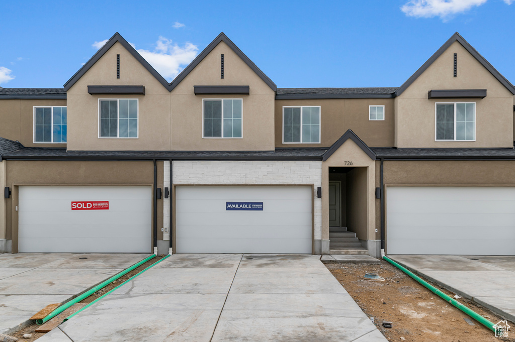 Multi unit property with stucco siding, an attached garage, and driveway