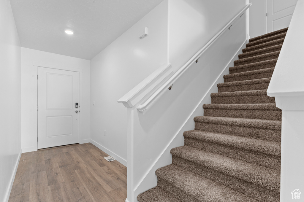 Stairway featuring baseboards, recessed lighting, wood finished floors, and visible vents