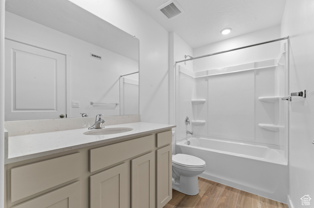 Full bathroom with vanity, toilet, wood finished floors, and visible vents