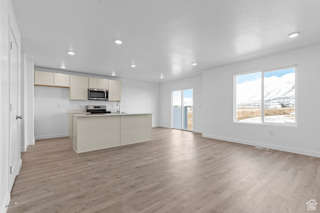 Unfurnished living room featuring recessed lighting, baseboards, and light wood finished floors