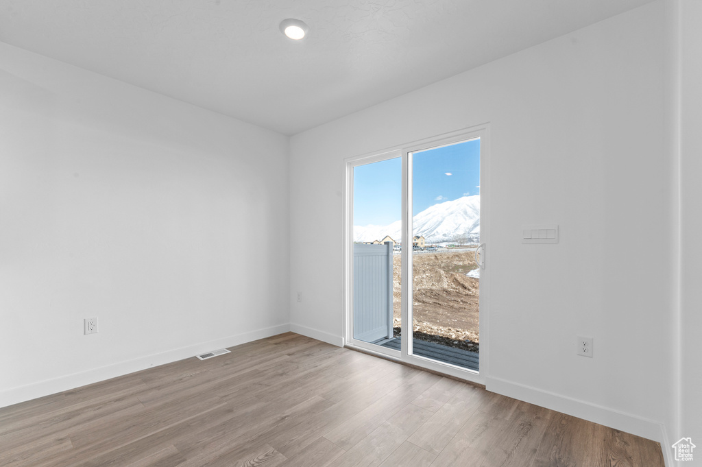 Spare room featuring visible vents, baseboards, and wood finished floors