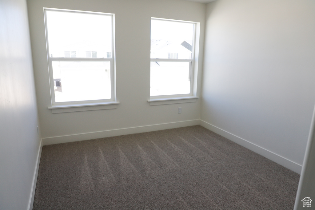 Carpeted spare room featuring baseboards