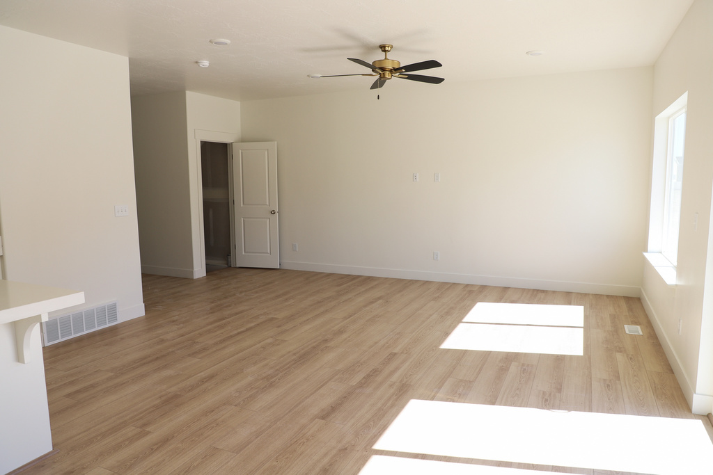 Empty room featuring baseboards, ceiling fan, visible vents, and light wood-style flooring