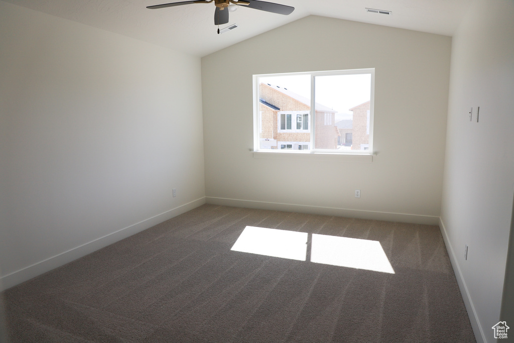 Unfurnished room featuring carpet floors, baseboards, ceiling fan, and lofted ceiling