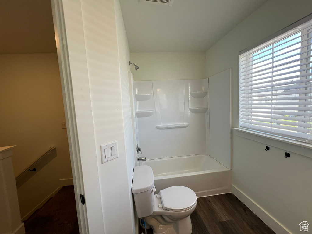 Full bathroom with toilet, baseboards, shower / bath combination, wood finished floors, and visible vents