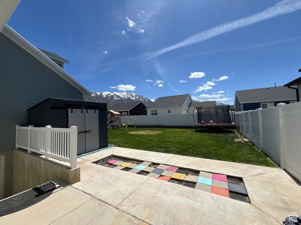 View of patio / terrace featuring a fenced backyard, a trampoline, a playground, and a mountain view
