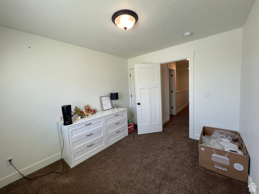 Bedroom featuring baseboards and dark carpet