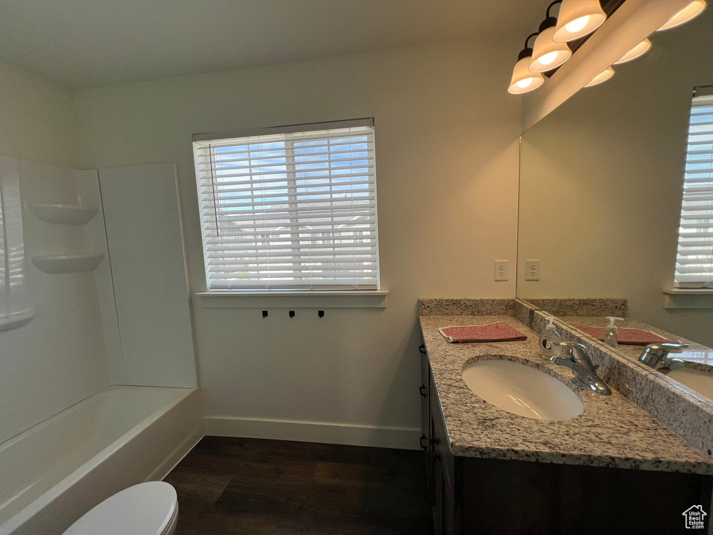 Bathroom with vanity, baseboards, toilet, and wood finished floors