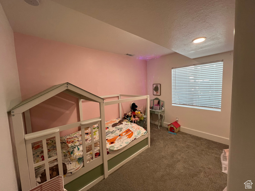 Carpeted bedroom with baseboards, a textured ceiling, and visible vents