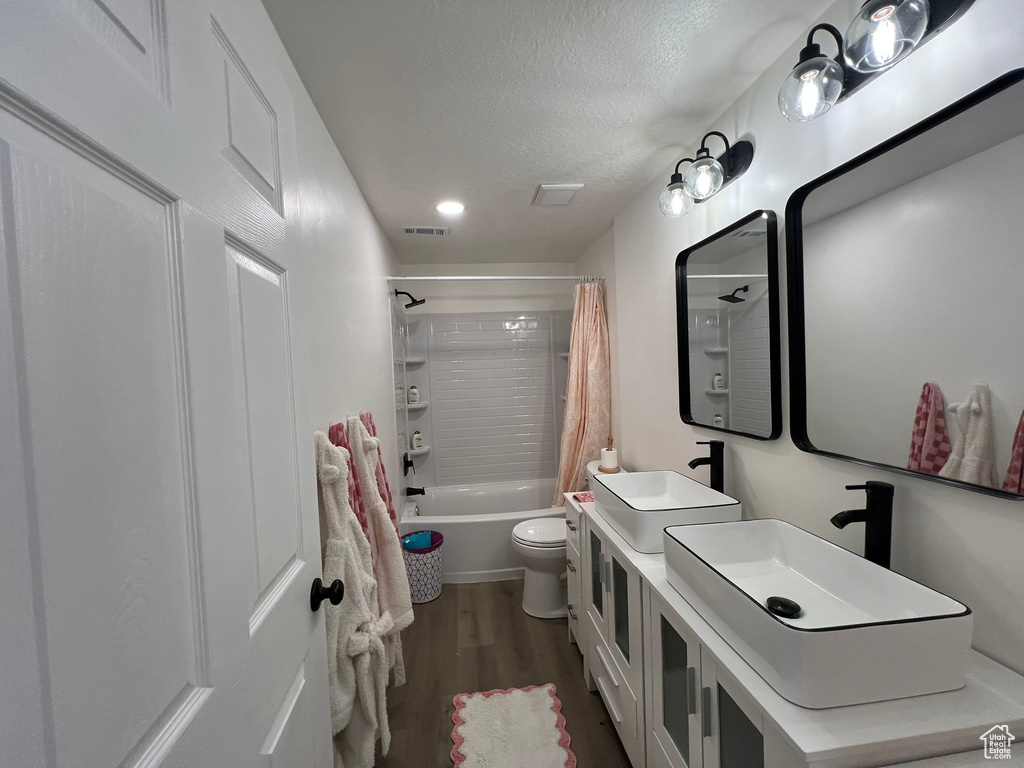 Full bathroom featuring visible vents, wood finished floors, toilet, shower / bathtub combination with curtain, and a sink