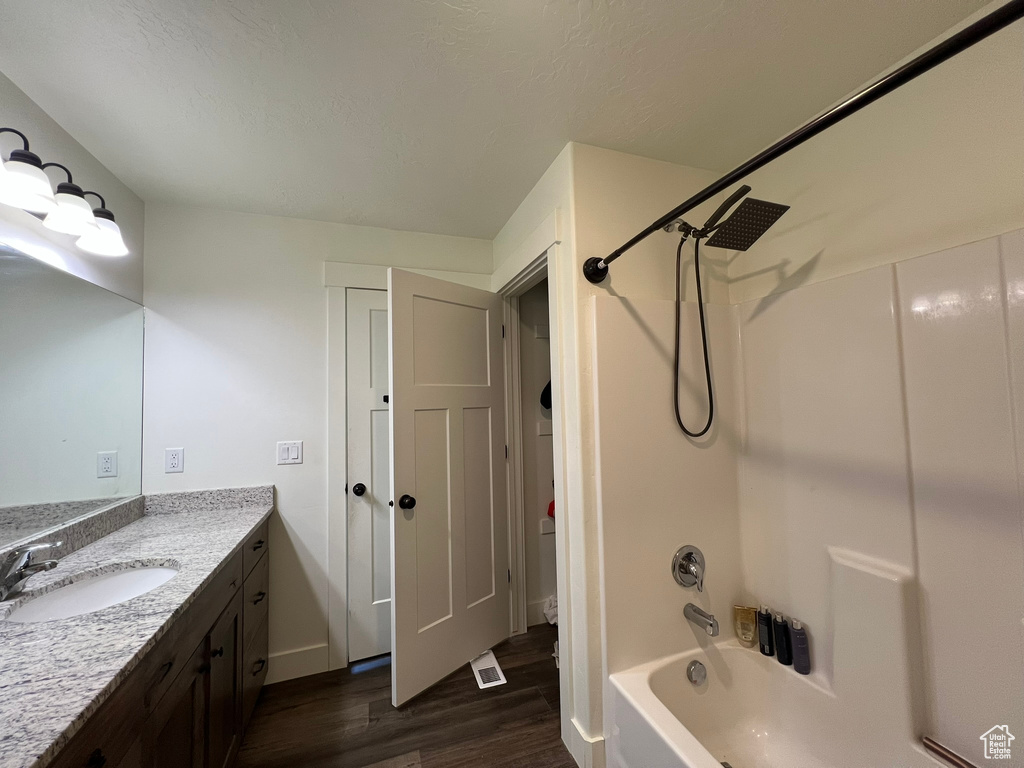 Full bathroom with vanity, baseboards, washtub / shower combination, and wood finished floors