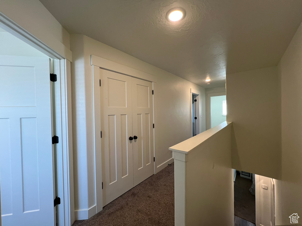 Hallway featuring dark carpet, recessed lighting, baseboards, and an upstairs landing