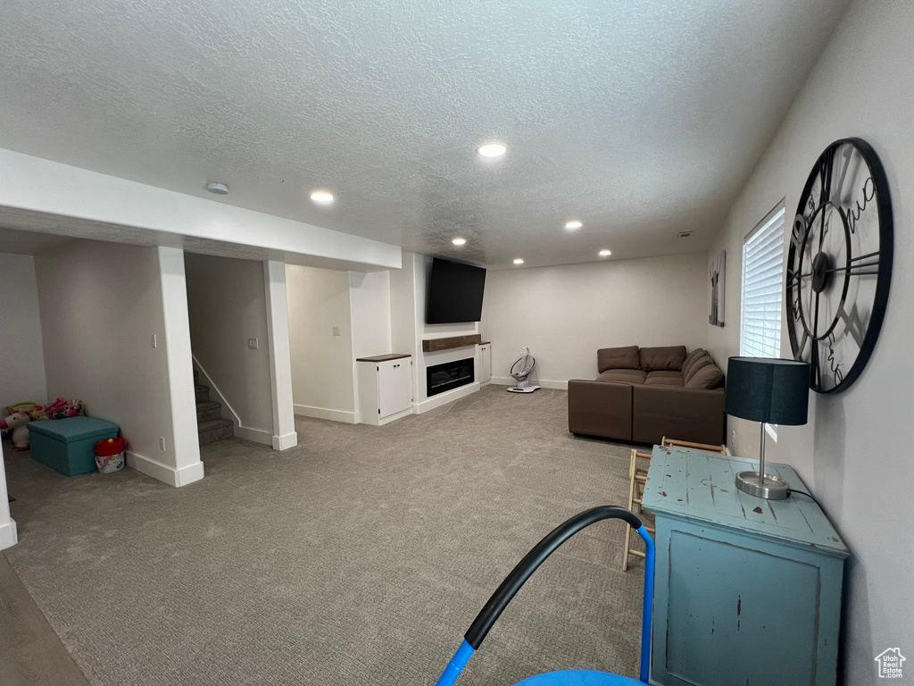 Living area with recessed lighting, a textured ceiling, baseboards, and stairway