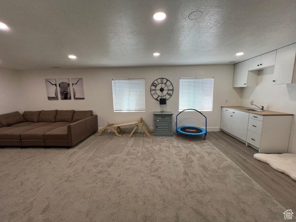 Living room with recessed lighting, baseboards, a textured ceiling, and wood finished floors