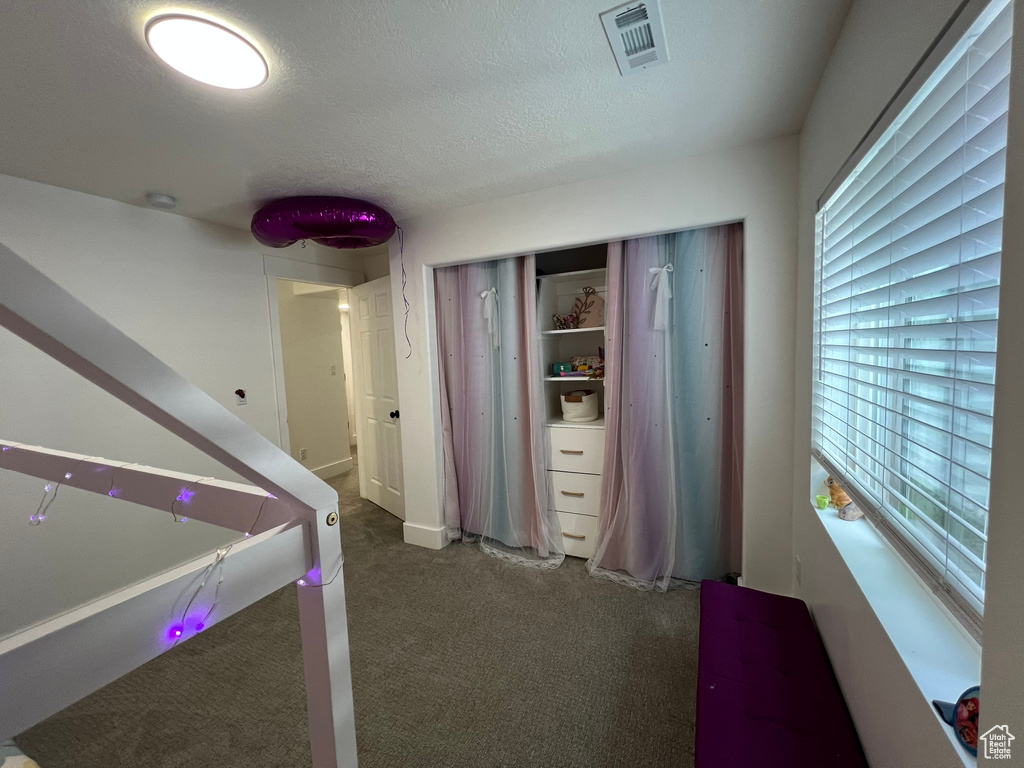 Interior space with a textured ceiling, visible vents, and carpet