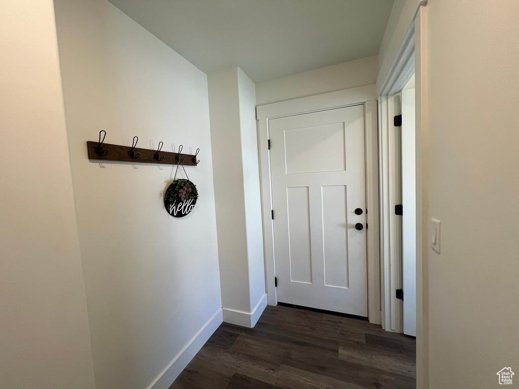 Doorway featuring baseboards and dark wood finished floors