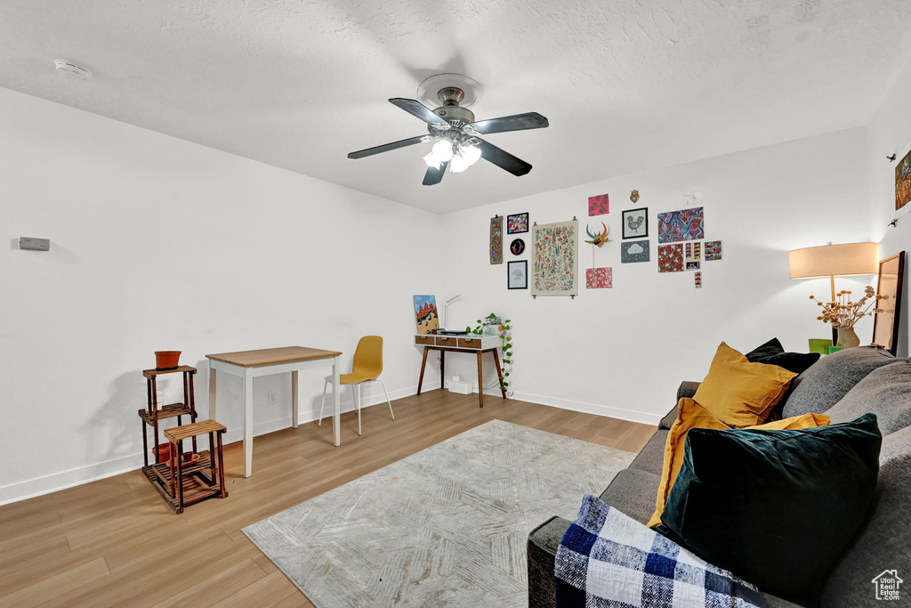 Sitting room featuring light wood-style floors, a ceiling fan, and baseboards