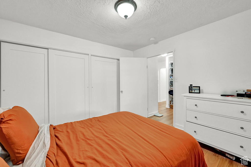 Bedroom with light wood-style flooring, two closets, and a textured ceiling
