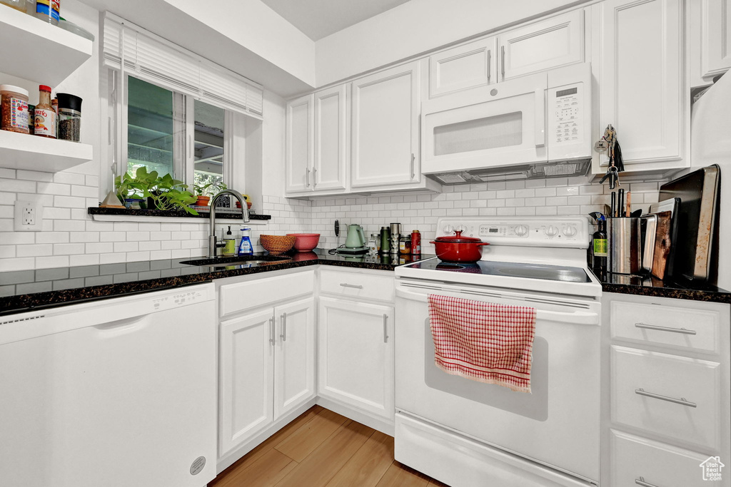 Kitchen featuring a sink, white cabinets, white appliances, and tasteful backsplash
