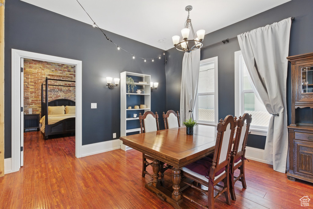Dining room featuring baseboards, wood finished floors, and a notable chandelier