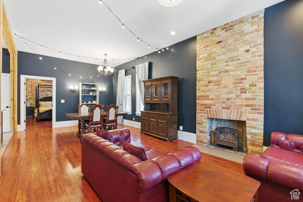 Living room with baseboards, an inviting chandelier, hardwood / wood-style flooring, and a fireplace