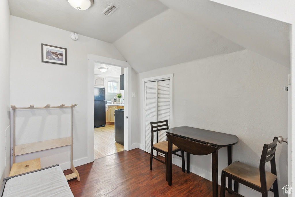 Interior space with baseboards, vaulted ceiling, wood finished floors, and visible vents