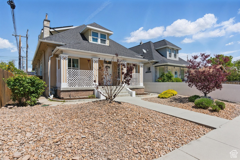 Bungalow-style house with a porch, a shingled roof, a chimney, and fence private yard