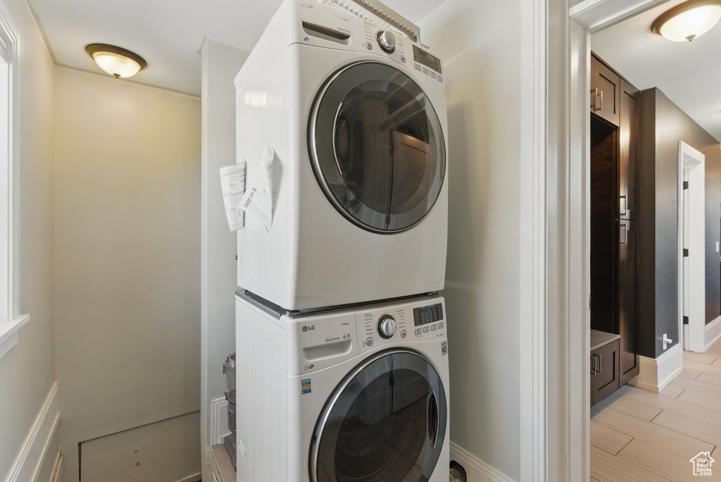 Washroom featuring stacked washer and dryer, laundry area, and baseboards