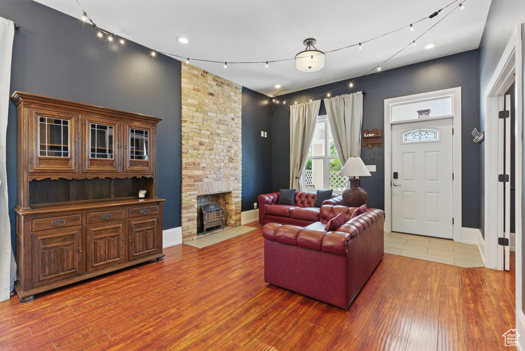 Living room featuring baseboards, a stone fireplace, recessed lighting, and wood finished floors