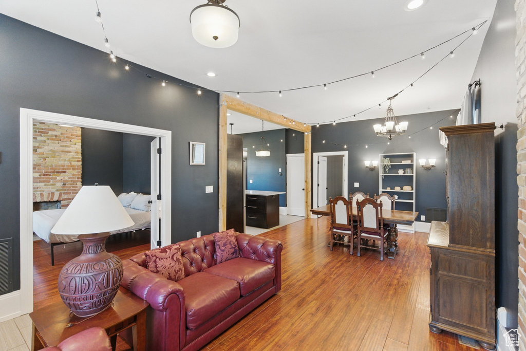 Living room featuring wood-type flooring, a notable chandelier, visible vents, and a fireplace